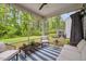 Screened porch with blue and white striped rug, wicker furniture and view of landscaped backyard at 2009 Latham Oaks Ave, Wake Forest, NC 27587