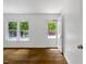 Bright, empty room featuring hardwood floors, fresh white paint, and multiple windows at 2085 Enon Rd, Oxford, NC 27565