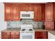 Kitchen featuring granite countertops, tile backsplash, wood cabinets, and white appliances at 25 Misty Way, Franklinton, NC 27525