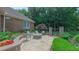 Landscaped backyard patio with a stone fire pit, seating area, and lush gardens enclosed by a decorative stone fence at 3197 Carriage Creek Ct, Haw River, NC 27258