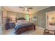 This primary bedroom includes a ceiling fan, large windows, and a decorative painting on the wall at 3197 Carriage Creek Ct, Haw River, NC 27258