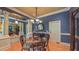 Elegant dining room featuring hardwood floors, a glass-top table, ornate columns, and designer lighting at 3197 Carriage Creek Ct, Haw River, NC 27258