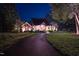 Charming brick home with a circular driveway, manicured lawn, and elegant exterior lighting at night at 3197 Carriage Creek Ct, Haw River, NC 27258