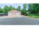 Outbuilding with two garage doors, covered storage and a gravel driveway at 3197 Carriage Creek Ct, Haw River, NC 27258