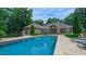 A luxurious brick home features a large, inviting pool surrounded by lush landscaping and comfortable lounge chairs at 3197 Carriage Creek Ct, Haw River, NC 27258