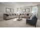 Spacious living room featuring neutral decor, two sofas, a gray accent chair, and large windows at 32 Elmwood Ave, Sanford, NC 27330