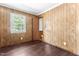 Bedroom with wood-paneled walls, hardwood floors, and window offering ample natural light at 403 S Webb St, Selma, NC 27576