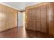 Bedroom with wood-paneled walls, hardwood floors, and closet with louvered doors at 403 S Webb St, Selma, NC 27576
