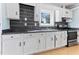 Traditional kitchen features white cabinets, black counters and updated backsplash at 403 S Webb St, Selma, NC 27576