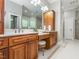 Bathroom featuring double vanity sinks, warm wood cabinets, tile flooring, and a large mirror at 540 Vista Del Lago Ln, Wake Forest, NC 27587