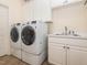 Functional laundry room with modern washer and dryer, utility sink, and white cabinetry at 540 Vista Del Lago Ln, Wake Forest, NC 27587