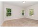 A light filled bedroom featuring three windows and neutral carpeting at 66 Sweet Meadow Ln, Pittsboro, NC 27312