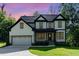 Stunning two-story home with white siding, black trim, attached garage, and manicured front lawn at sunset at 66 Sweet Meadow Ln, Pittsboro, NC 27312