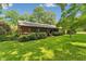 Inviting backyard featuring lush green grass, mature trees, and a charming home exterior with a wooden deck, perfect for outdoor living at 6971 Shady Creek Trl, Rougemont, NC 27572