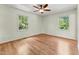 Bright bedroom with hardwood floors, two windows with scenic views, and a ceiling fan, providing a comfortable and airy atmosphere at 6971 Shady Creek Trl, Rougemont, NC 27572