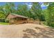 View of the side and rear of home showcasing wood siding, deck and ramp access to covered outdoor seating area at 6971 Shady Creek Trl, Rougemont, NC 27572