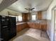Kitchen features wooden cabinets, window above sink, and black fridge in the corner at 705 Washington St, Graham, NC 27253
