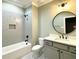 Modern bathroom featuring a tub and shower combination, a round mirror, and stylish fixtures at 80 Water Willow Ln, Zebulon, NC 27597