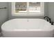 Freestanding bathtub with modern fixtures and a view of the home's exterior through a large window at 80 Water Willow Ln, Zebulon, NC 27597