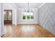 Bright dining room featuring hardwood floors, modern chandelier, and a feature wall with geometric design at 80 Water Willow Ln, Zebulon, NC 27597