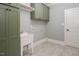 Laundry room featuring green cabinets, utility sink, and tiled floors, blending style with functionality at 80 Water Willow Ln, Zebulon, NC 27597