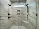 Modern shower with marble-style tiles, multiple shower heads, and a built-in bench for added comfort and style at 80 Water Willow Ln, Zebulon, NC 27597