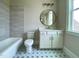 Bathroom with patterned floors, white vanity, bathtub, and round mirror at 90 Water Willow Ln, Zebulon, NC 27597
