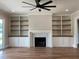 Bright living room with ceiling fan, hardwood floors, custom built-in shelving, and fireplace at 90 Water Willow Ln, Zebulon, NC 27597