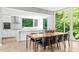 Dining room with kitchen view showcasing white countertops, appliances, and large windows with wooded view at 9021 Albatross Ct, Raleigh, NC 27613