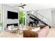 Elegant living area with a piano, modern fireplace, and glass staircase at 9021 Albatross Ct, Raleigh, NC 27613