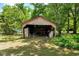Rustic open shed surrounded by greenery, providing storage and potential for various uses at 903 Nicholas St, Henderson, NC 27536