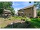 Backyard featuring a wooden playset, raised garden beds, and a large grassy area at 10205 Sorrills Creek Ln, Raleigh, NC 27614