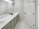 Bathroom with double sink vanity with gray cabinets, tile floors, large mirror and white door at 105 Crosswaite Way, Cary, NC 27518