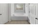 Bathroom featuring a soaking tub under a window, tiled floors, and white doors at 105 Crosswaite Way, Cary, NC 27518