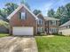 Charming two-story brick home with a well-manicured lawn, an attached two-car garage, and beautiful green window shutters at 105 Crosswaite Way, Cary, NC 27518