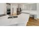 Bright kitchen with white quartz counters, gray cabinets, a stainless steel refrigerator and hardwood floors at 105 Crosswaite Way, Cary, NC 27518