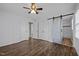 Bright bedroom featuring wood-look floors, a ceiling fan, and a sliding barn door to the en-suite bathroom at 1195 Champion Dr, Cary, NC 27511