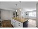 Kitchen island with granite countertop and pendant lighting, with wood floors extending into the dining area at 1195 Champion Dr, Cary, NC 27511