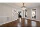 Refined dining room showcases hardwood floors, wainscoting, a statement chandelier, and views of the entryway and sunlit windows at 1475 Sierra Glen Cir, Apex, NC 27502