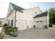 Spacious three-car garage with white doors and extra driveway space, framed by lush landscaping at 1475 Sierra Glen Cir, Apex, NC 27502