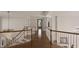 Bright hallway with wood floors, and decorative railing leads to other rooms of the home at 1475 Sierra Glen Cir, Apex, NC 27502