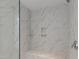 Close-up of luxurious marble shower featuring a built-in bench seat and recessed shelving at 1475 Sierra Glen Cir, Apex, NC 27502
