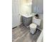 This bathroom features gray cabinets, white tile shower, and wood-look floors at 1602 Fairground Rd, Dunn, NC 28334