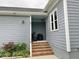 Exterior entryway with a brick staircase, covered porch, and muted blue walls at 1944 Castle Pines Dr, Raleigh, NC 27604