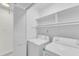 Bright laundry room with washer, dryer, storage shelves, and white door at 2204 Bellaire Ave, Raleigh, NC 27608
