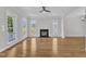 Spacious living room featuring hardwood floors, ceiling fan, fireplace, and large bright windows at 2204 Bellaire Ave, Raleigh, NC 27608