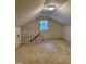 Cozy attic featuring carpet, lighting, and a window for natural light at 225 Meadow Dr, Henderson, NC 27537