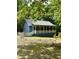 Charming blue cabin featuring a spacious porch with a white railing and situated on a lush, wooded lot at 225 Meadow Dr, Henderson, NC 27537