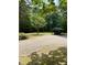 A home boasts a spacious gravel driveway with a carport surrounded by lush green trees at 225 Meadow Dr, Henderson, NC 27537