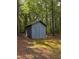 Exterior view of a shed in the wooded backyard with green grass and pine needles at 225 Meadow Dr, Henderson, NC 27537